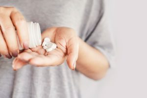 woman pouring pills into hand as she is thinking about the benefits of medication assisted treatment