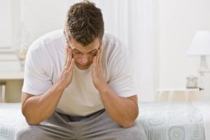 man sitting on edge of bed working to prevent addiction relapse