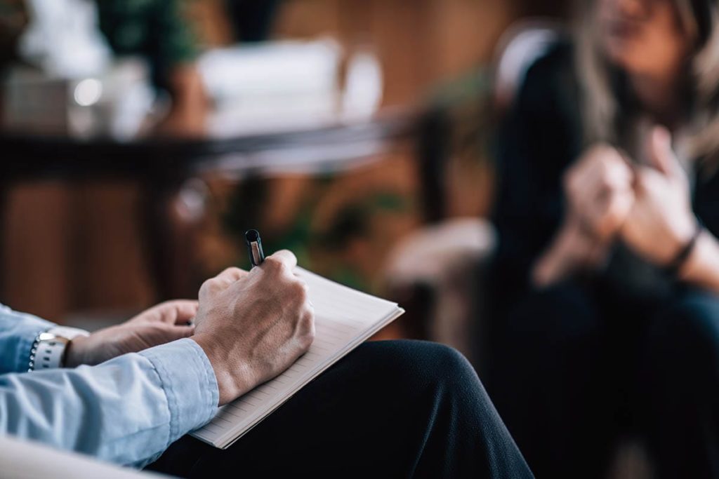 man writing in notebook about choosing a residential treatment