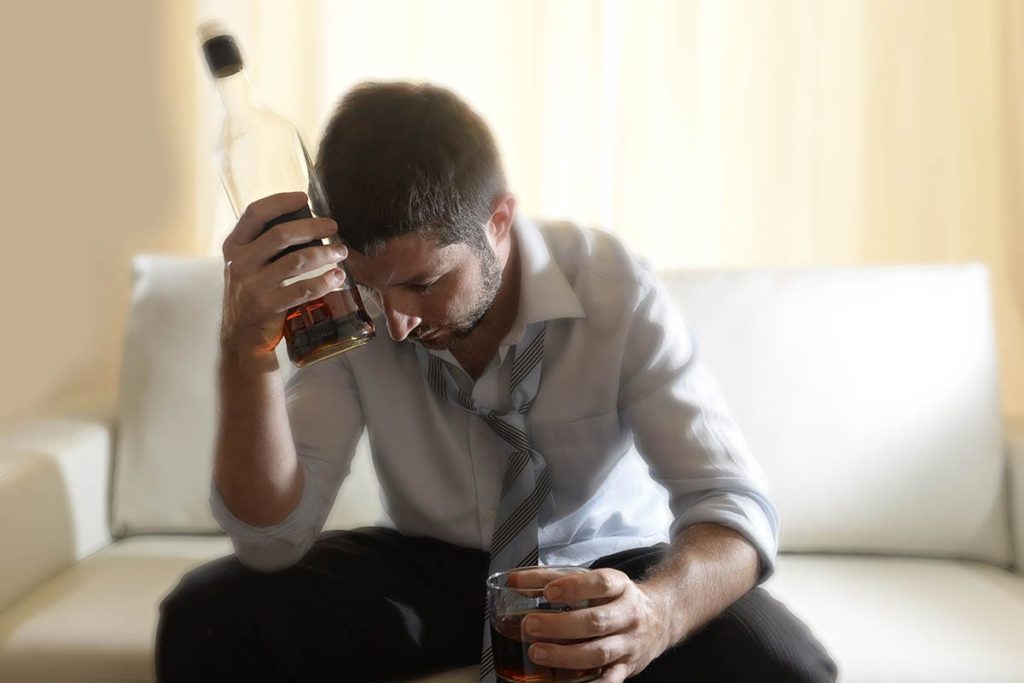 man drinking alcohol showing signs of alcoholism
