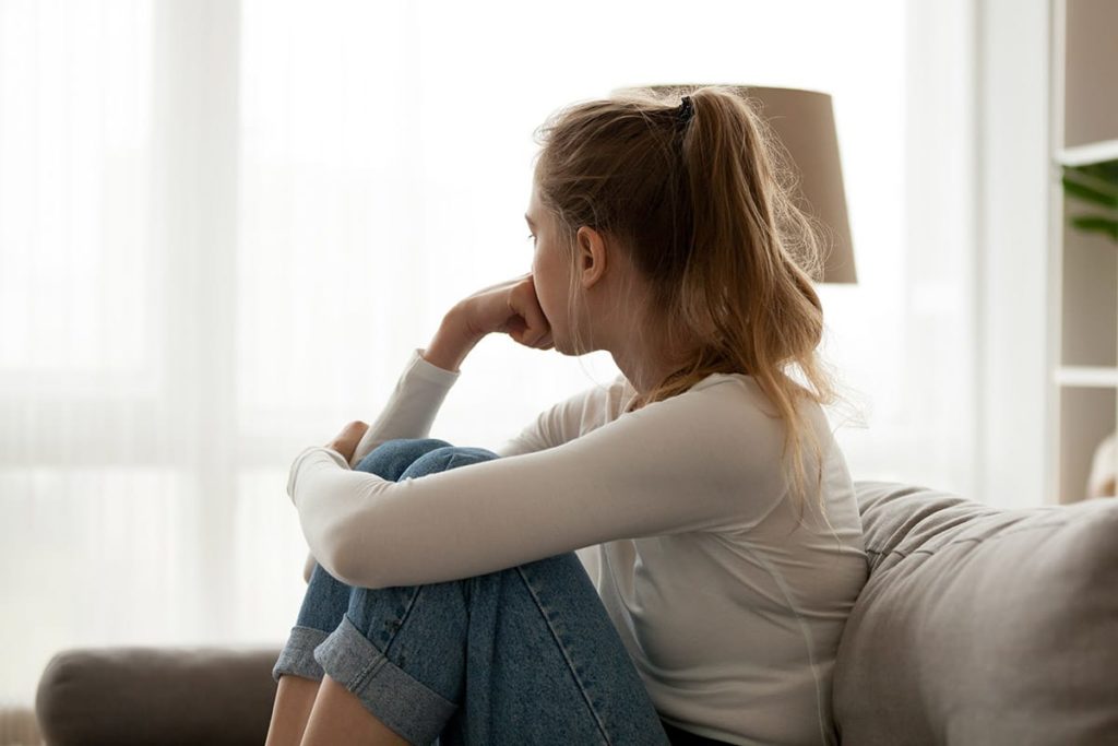 a woman sitting on her couch thinking about the long-term effects of prescription painkiller abuse