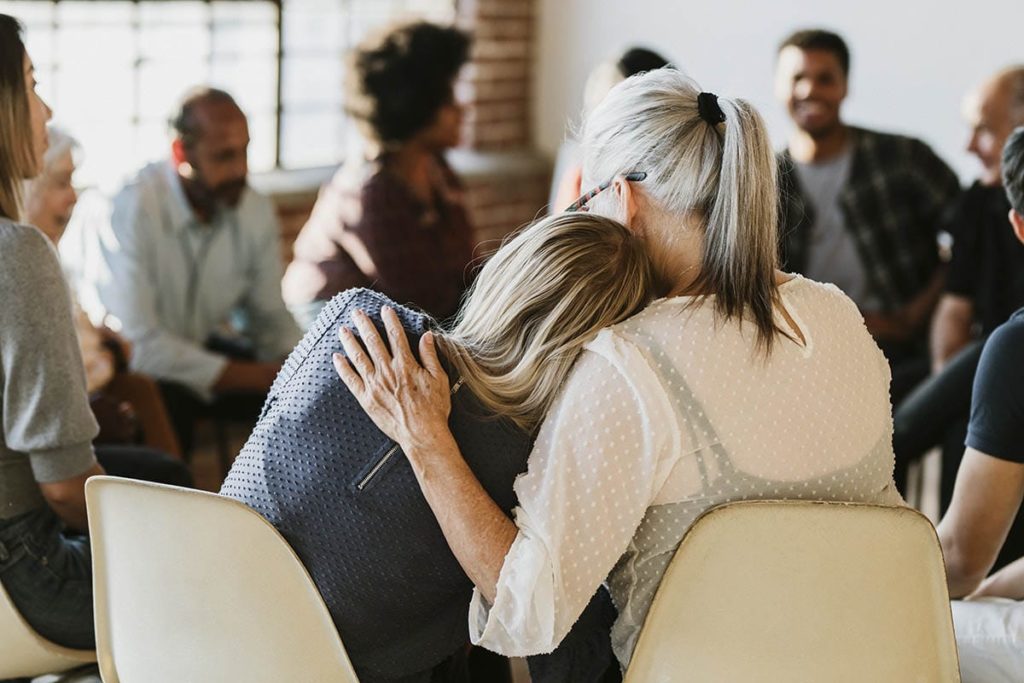 a woman leaning on her friend and learning what to expect during an intensive outpatient program