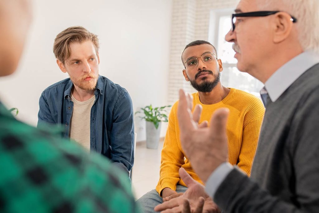 a group of men talking about why choose a men's addiction rehab center