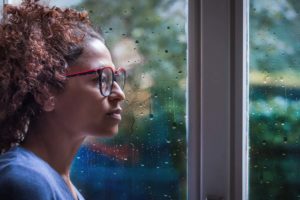 woman looking out window after relapse
