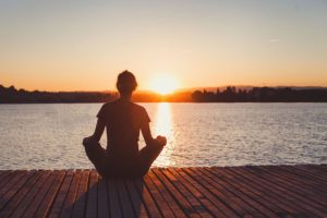 a woman sits on a dock and wonders about reasons to choose holistic treatment